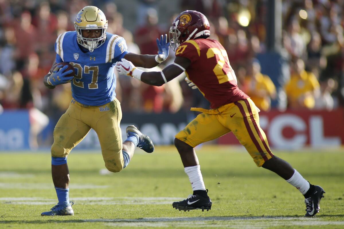 UCLA running back Joshua Kelley pushes off USC cornerback Ajene Harris in 2018.