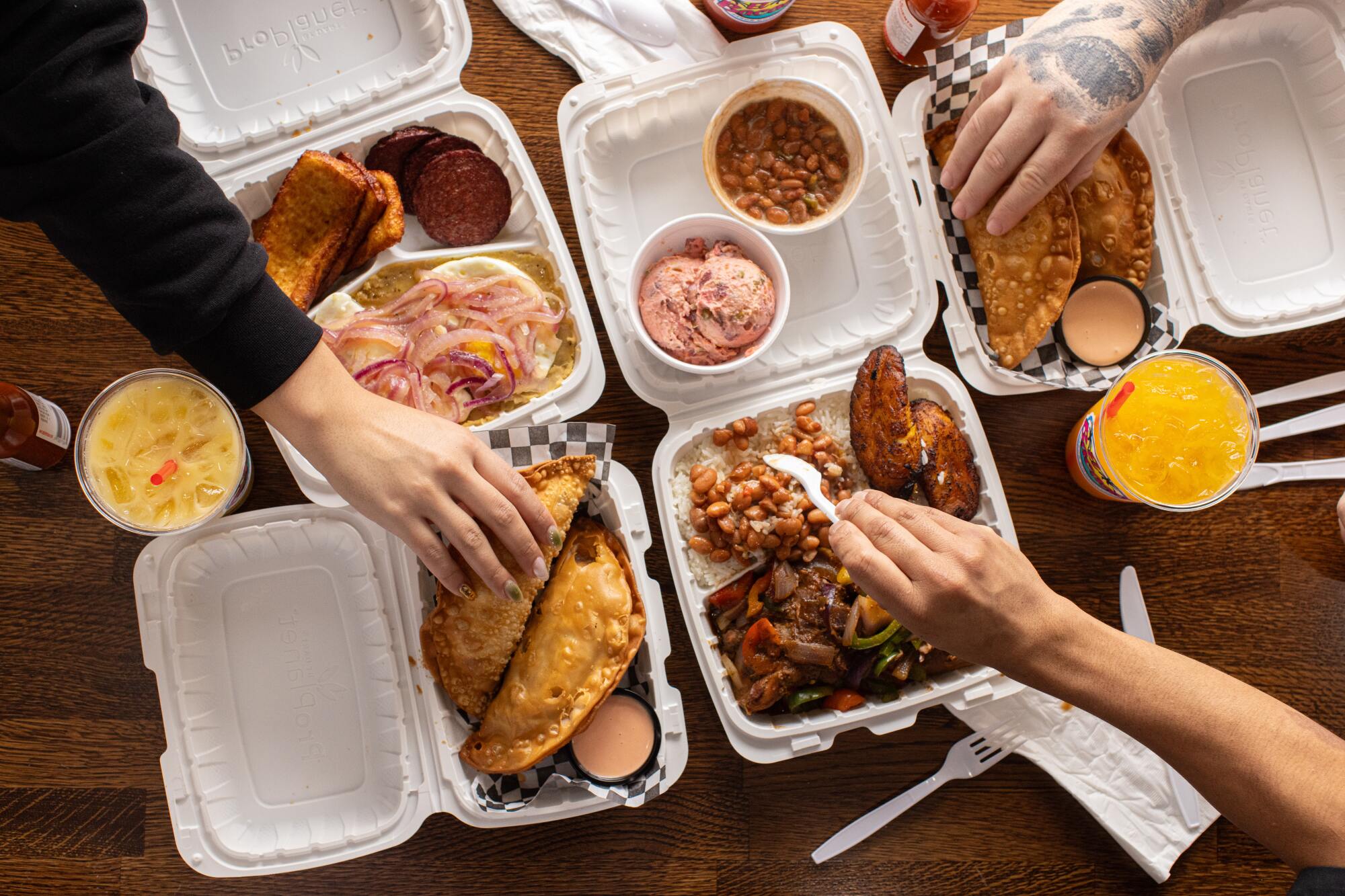 Hands reach over five Styrofoam containers of food from El Bacano. 