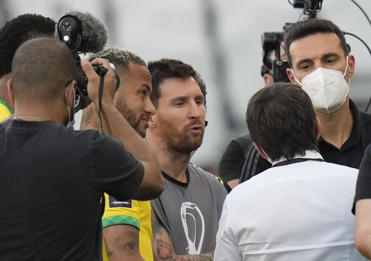 Argentina's Lionel Messi, center, Brazil's Neymar, left, and Argentina's coach Lionel Scaloni talk as the soccer game is interrupted by health authorities during a qualifying soccer match for the FIFA World Cup Qatar 2022 at Neo Quimica Arena stadium in Sao Paulo, Brazil, Sunday, Sept.5, 2021. (AP Photo/Andre Penner)