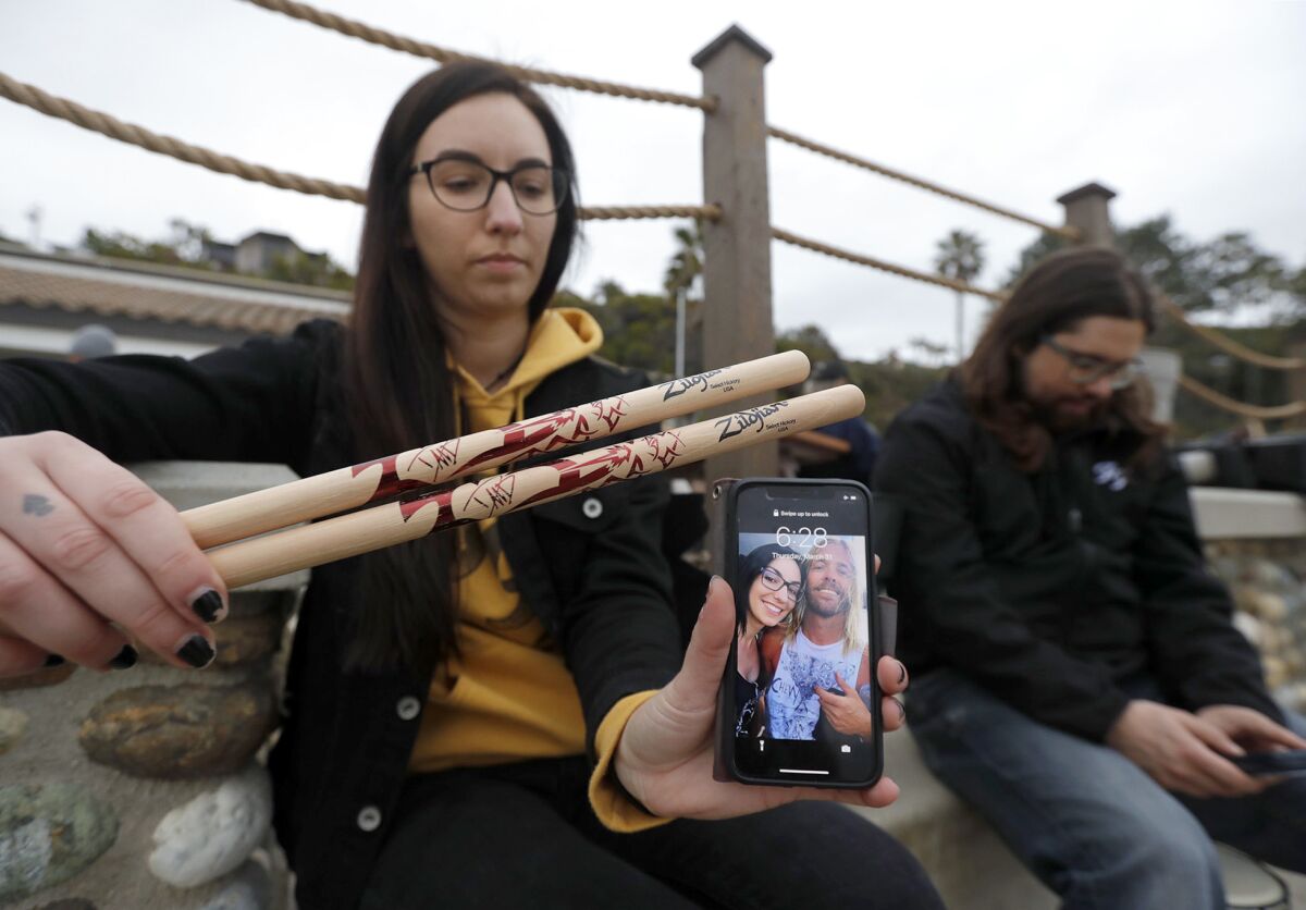 Sonia Daigle shows drumsticks given to her by Dave Grohl and a picture with Taylor Hawkins during a remembrance drum circle.