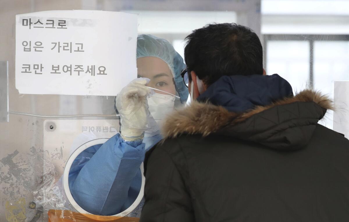 Una trabajadora médica, usando equipo protector, toma una muestra de un hombre 