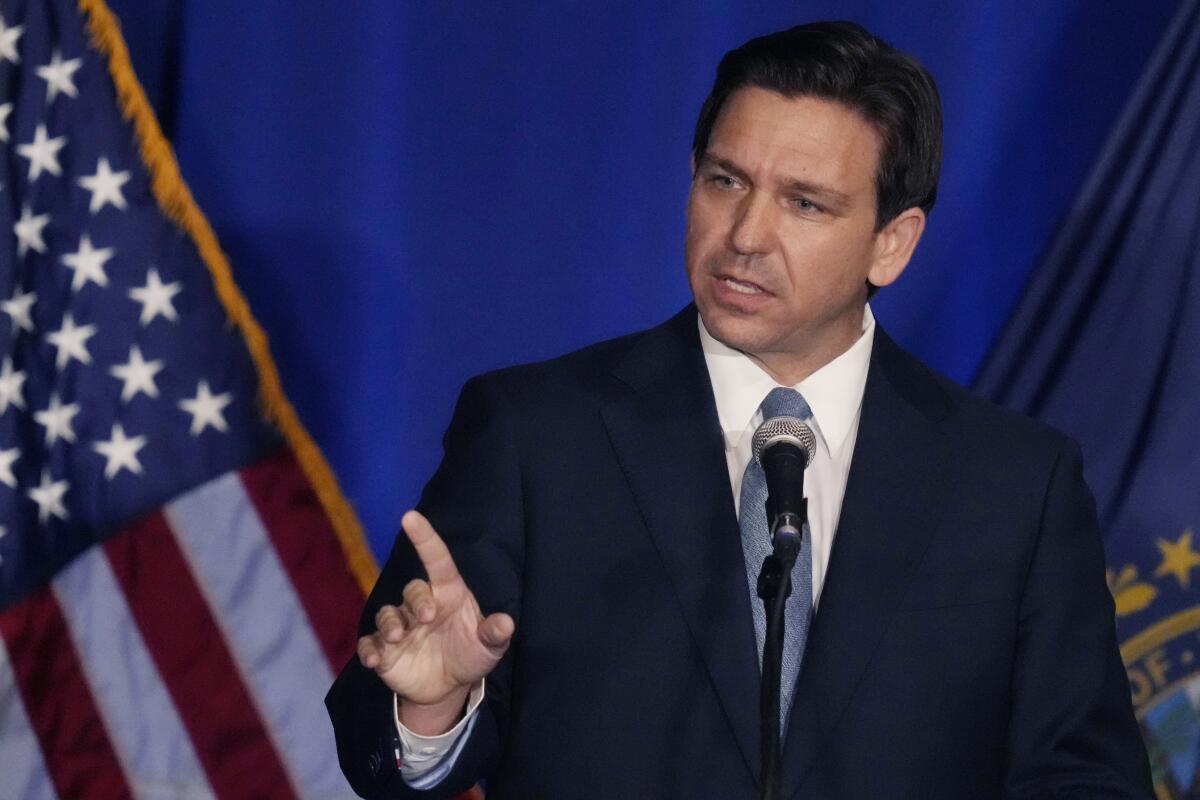 Florida Gov. Ron DeSantis gesturing as he speaks in front of a flag