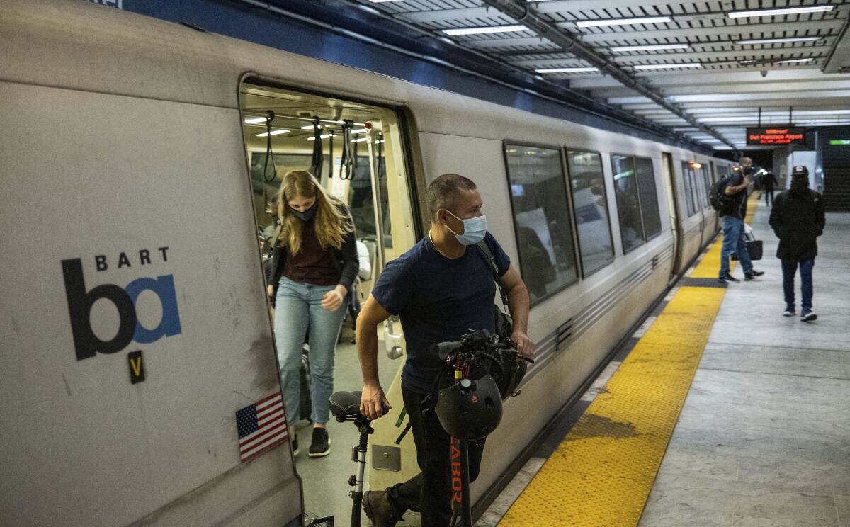Passengers wearing masks depart a BART train in San Francisco, Calif.