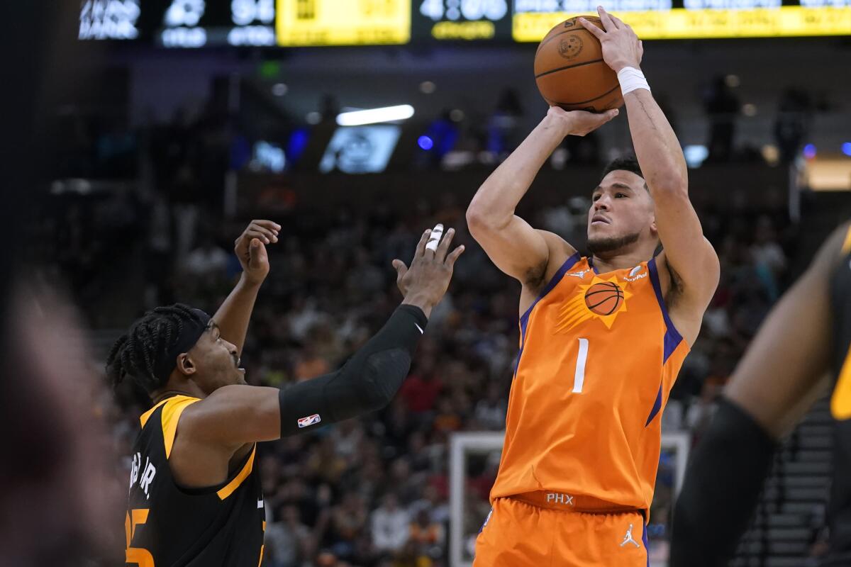 Phoenix Suns guard Devin Booker (1) shoots as Utah Jazz forward Danuel House Jr. (25) defends during the second half of an NBA basketball game Friday, April 8, 2022, in Salt Lake City. (AP Photo/Rick Bowmer)