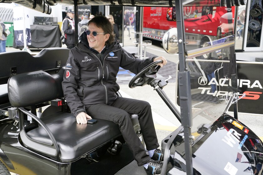 Team owner Wayne Taylor drives a golf cart through the garages after a practice session for the Rolex 24 hour auto race at Daytona International Speedway, Friday, Jan. 28, 2022, in Daytona Beach, Fla. (AP Photo/John Raoux)