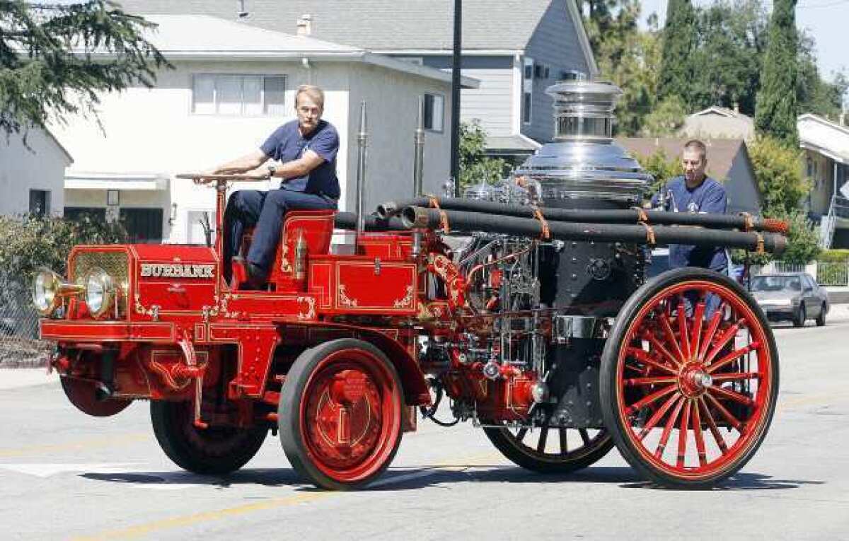 Burbank Fire engineers Terry Mencuri and Kevin Deagon ride a 1915 Christie Front Drive Tractor pulling a 1906 Christie Steam Pumper onto Thornton Avenue in Burbank at Burbank Fire Station 13. The trucks, acquired from Warner Bros. and originally used by the Los Angeles Fire Department, were restored by firemen at the station interested in preserving the department's history. The mechanical history is now being passed on to the newer fireman.