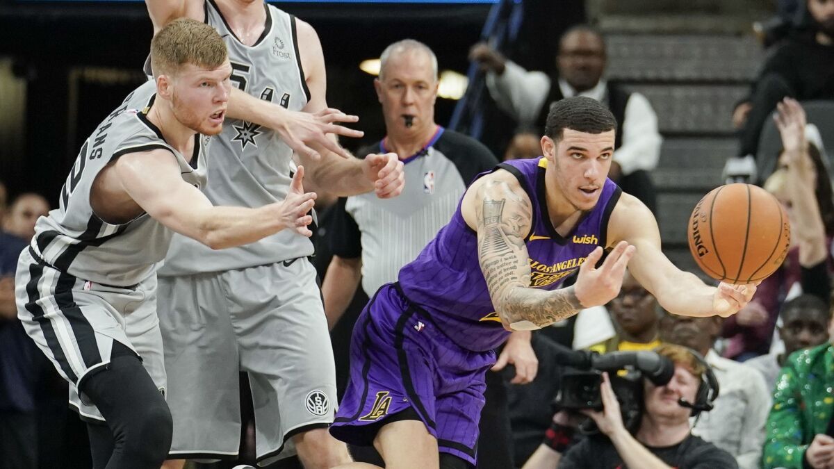 Lakers' Lonzo Ball, right, passes the ball as he evades San Antonio Spurs' Davis Bertans during the second half.