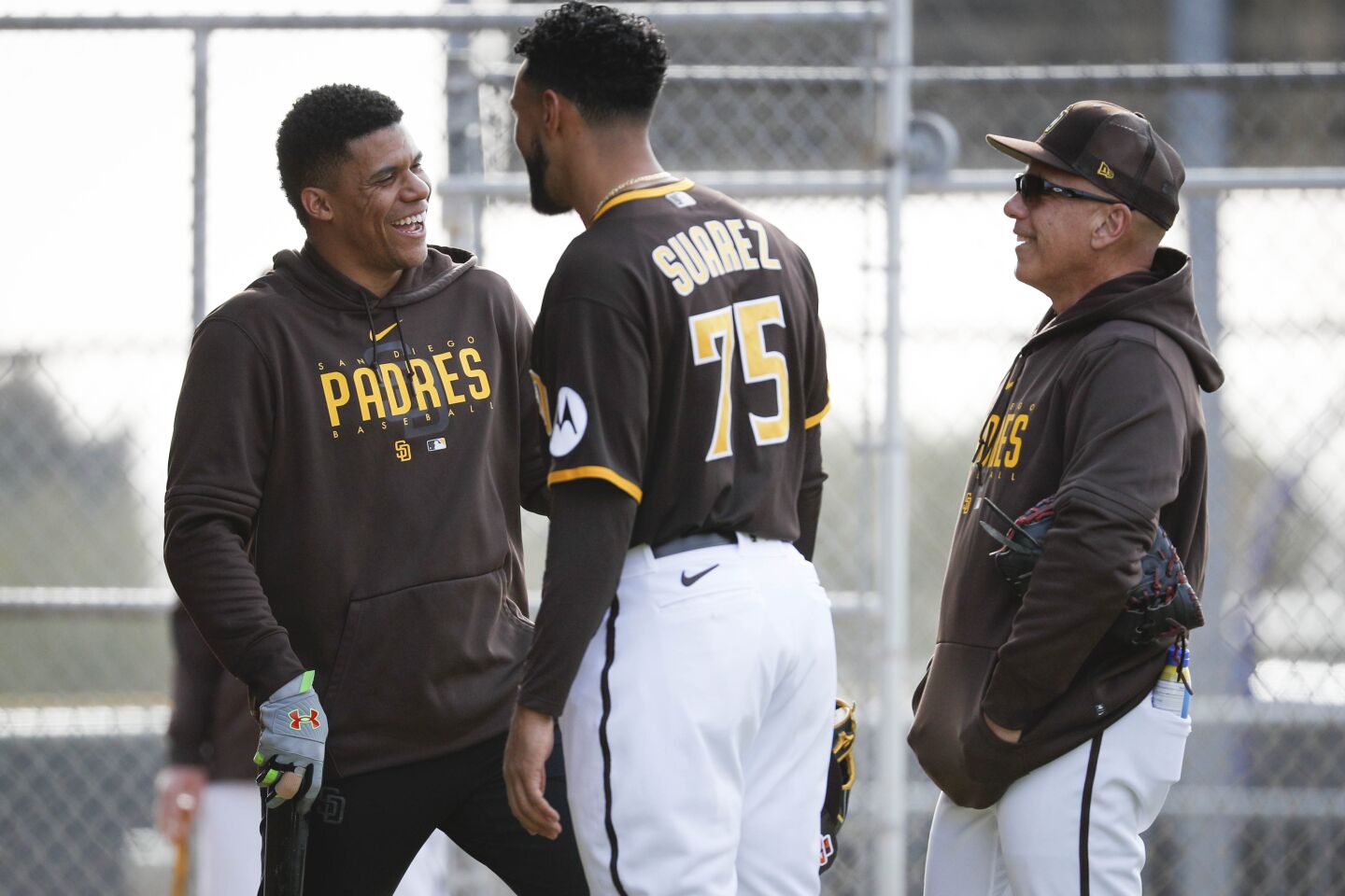 Padres right fielder Juan Soto (22) and relief pitcher Robert Suarez (75) chat with coaching stuff during a spring training practice at Peoria Sports Complex on Friday.