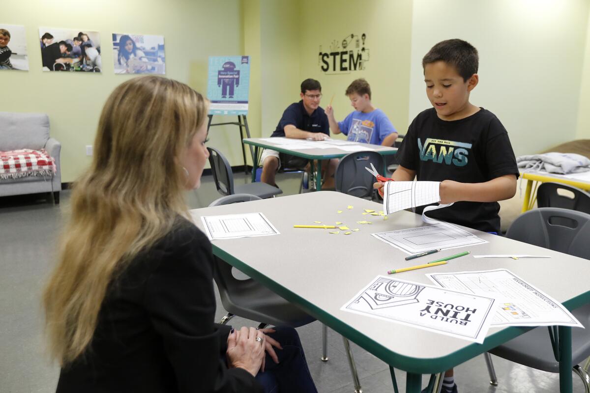 Principal Lisa Reid, left, and math teacher Joel Galloway, top left, work with fourth-graders in the Innovation Lab at STEM3 Academy in Irvine.