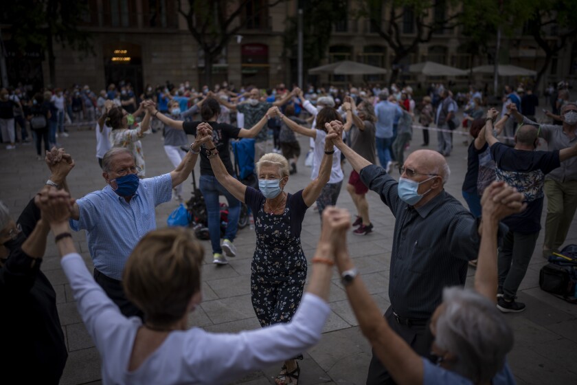 People wearing face masks to protect against the spread of Coronavirus dance "Sardana", a traditional Catalan dance, in front of the cathedral in Barcelona, Spain, Saturday, June 5, 2021. (AP Photo/Emilio Morenatti)