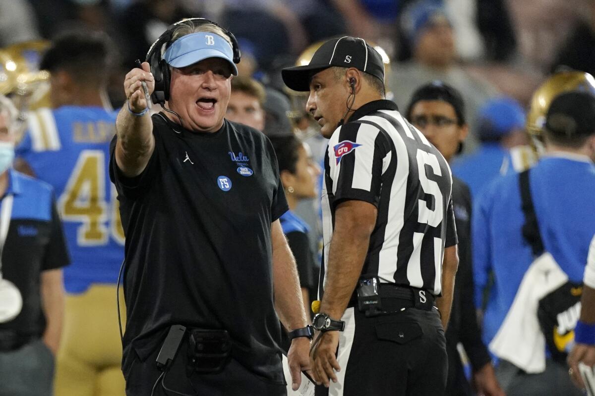 UCLA head coach Chip Kelly, left, talks to an official during a game against Arizona State