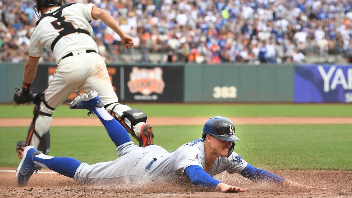 Dodgers' Enrique Hernandez dives to score a run against the Giants in the fourth inning.