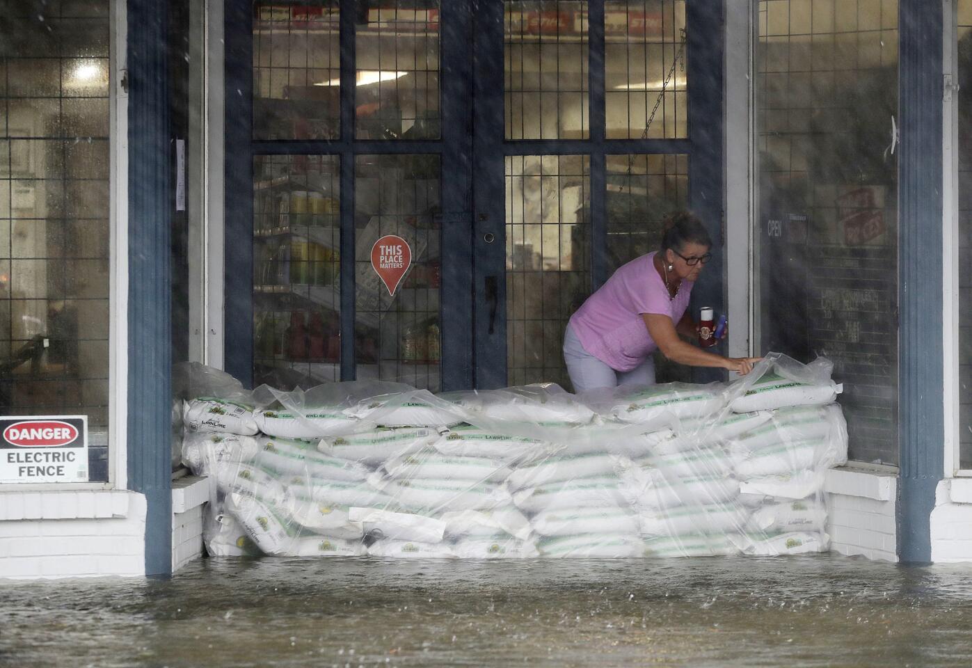 Debbie Tait checks on sand bags in the entrance to her hardware store as the street floods with water from Hurricane Matthew in downtown Brunswick, Ga., on Oct. 7, 2016.