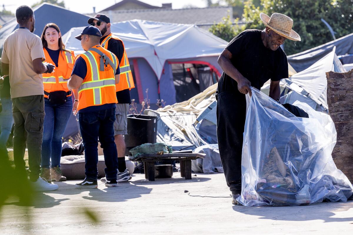  A man gathers belongings in an encampment after Inside Safe initiative employees got him a place to stay.