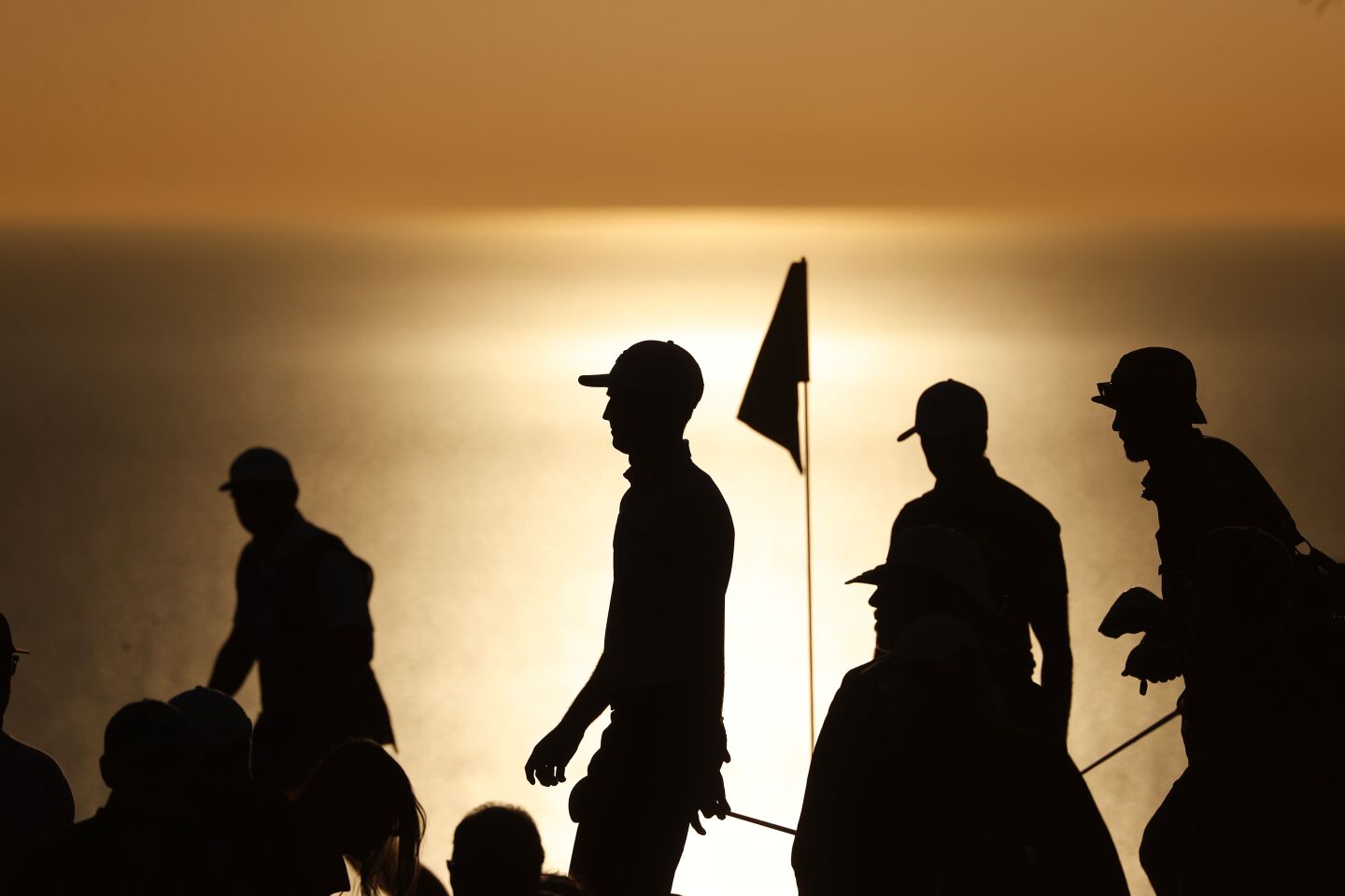 As the sun begins to set, golfers pass the 17th hole during the fourth round of the Farmers Insurance Open at Torrey Pines Golf Course in La Jolla on Jan. 29.