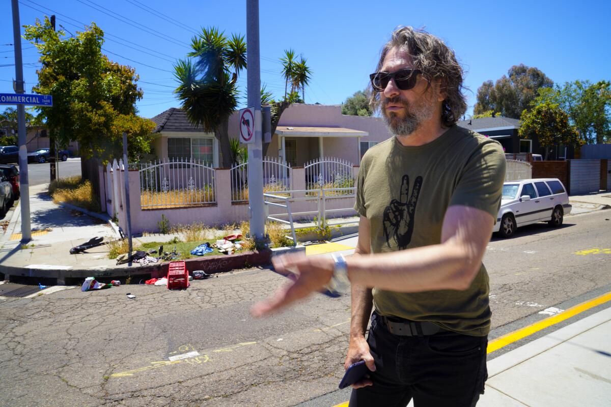 John Mireles, a Logan Heights property owner, gestures at trash on a corner of Commercial Street.