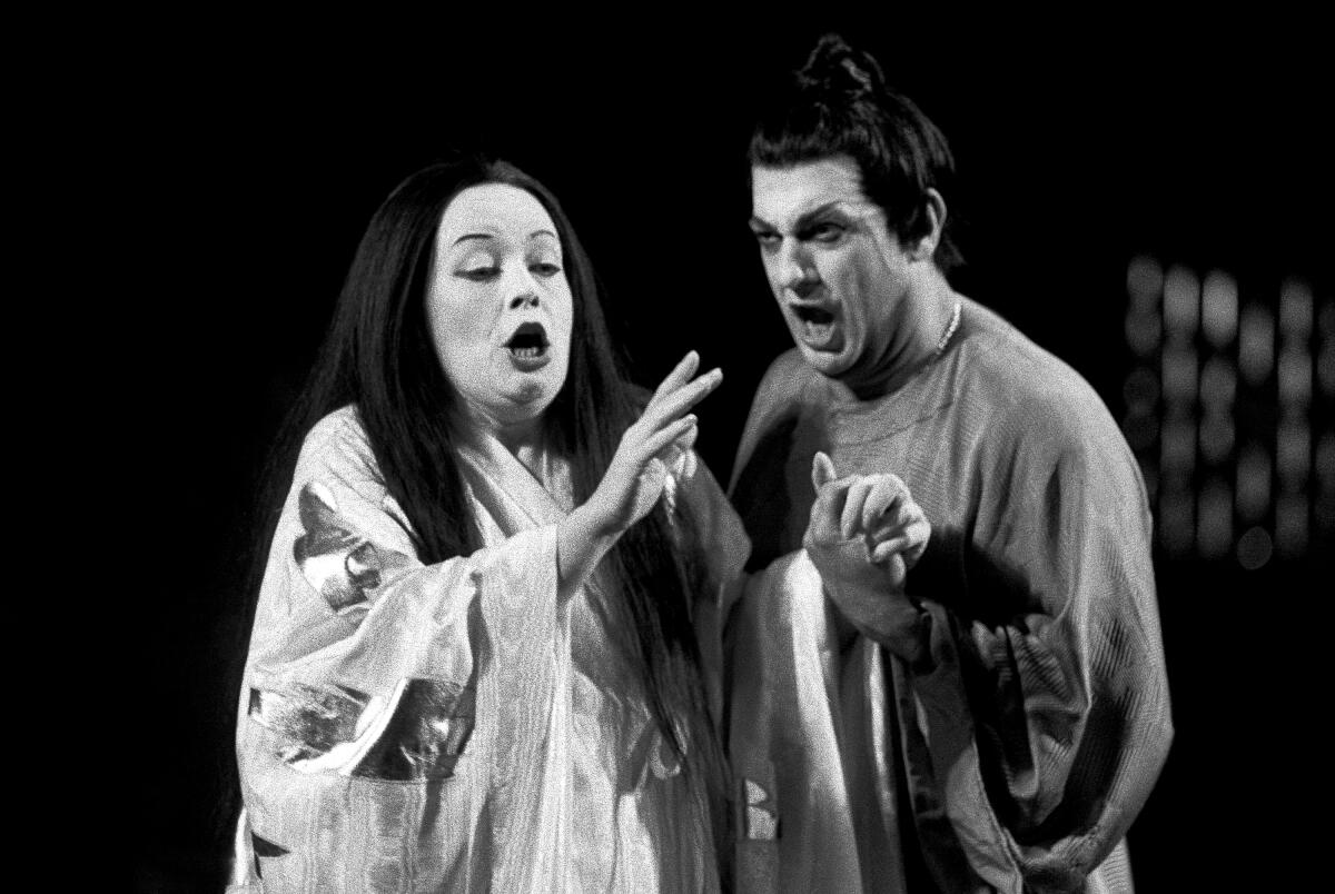A black-and-white photo of a woman and a man in kimonos, singing