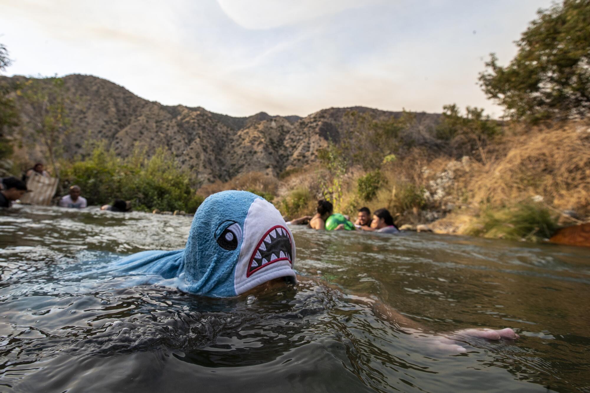 Friends and family of Matthew Giron, 8, frolic near a drainage pipe along the San Gabriel River.