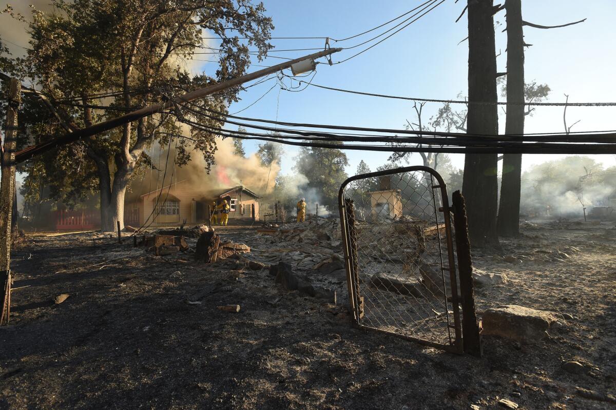 Firefighters work to control flames as a home burns in the town of Lower Lake, Calif.