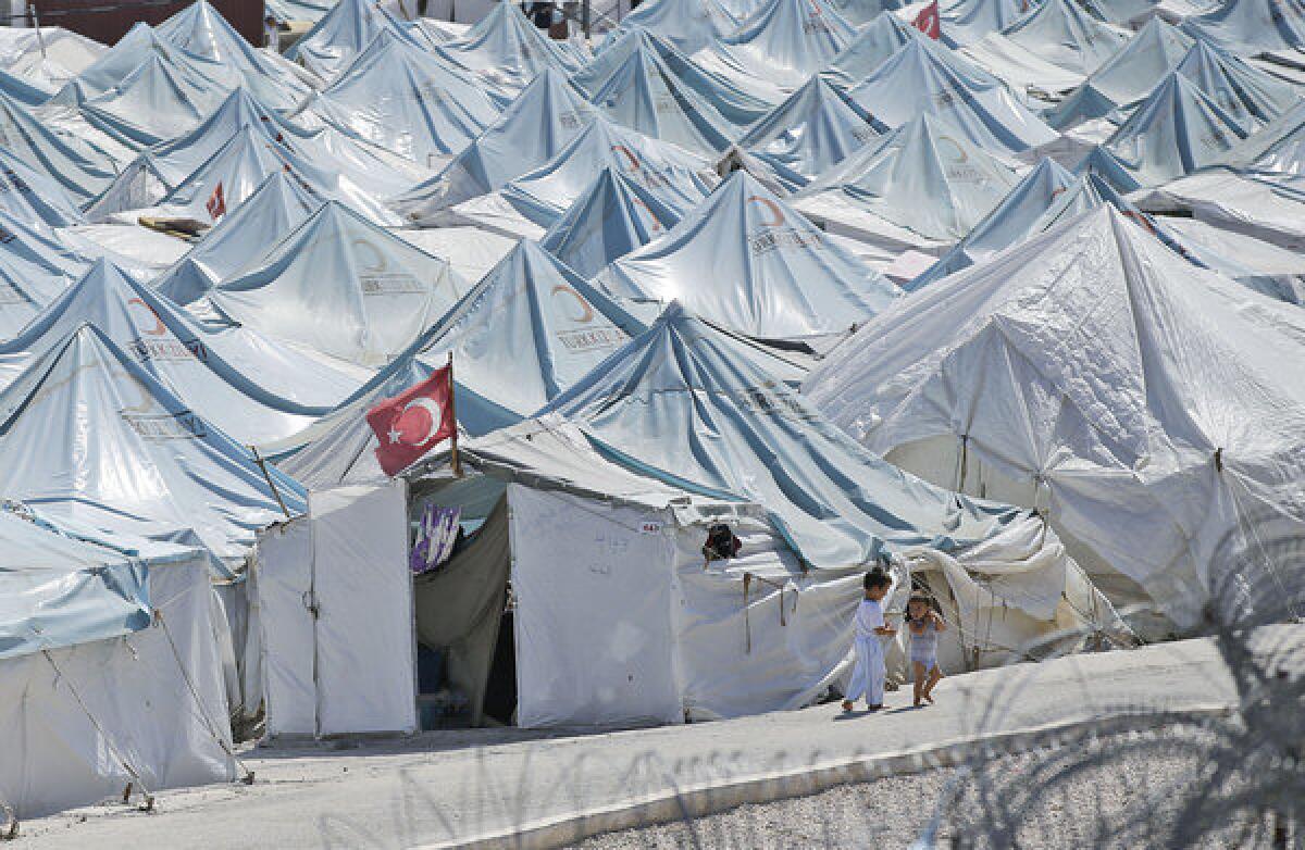 Children walk past tents at a Syrian refugee camp in Yayladagi, Turkey.