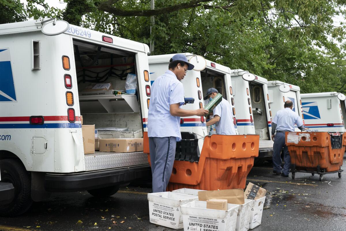 Postal Service workers load mail trucks.