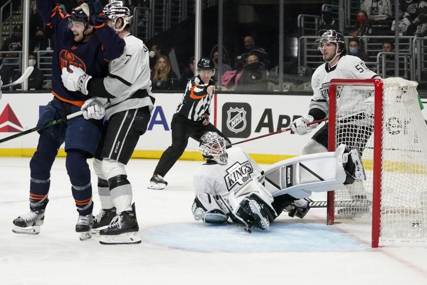 Edmonton Oilers left wing Warren Foegele, left, celebrates a goal by center Ryan Nugent-Hopkins while being pushed away by Los Angeles Kings defenseman Tobias Bjornfot, second from left, as goaltender Cal Petersen, second from right, sits in the crease during the third period of an NHL hockey game Tuesday, Feb. 15, 2022, in Los Angeles. (AP Photo/Mark J. Terrill)