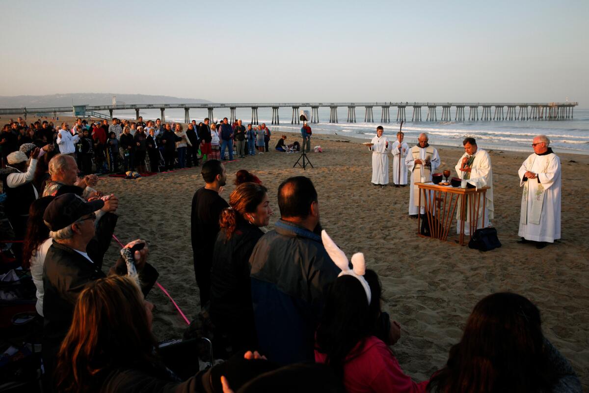 Bishop Alexander Salazar, center, and Pastor Raymond Mallett, right, celebrate Easter Sunday Mass at sunrise on the beach with the congregation of Our Lady of Guadalupe Hermosa Beach Catholic Church.
