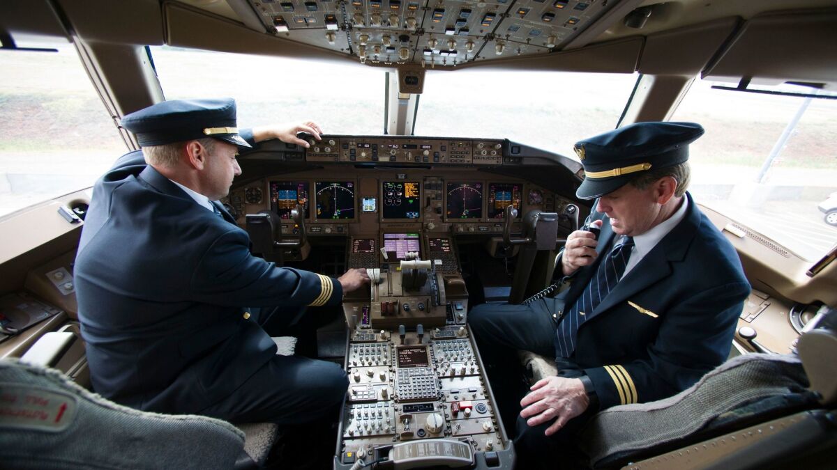The lighter paper results in shedding 1 ounce from each magazine. Above United Airlines Capt. Tommy Holloman, left, and Capt. Chuck Stewart demonstrate radio communications from the cockpit of a Boeing 777.