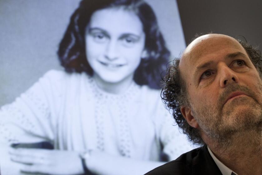 A picture of Anne Frank is projected as director Ronald Leopold of the Anne Frank Foundation listens during a press conference at the foundation's office in Amsterdam, Netherlands, Tuesday, May 15, 2018. Researchers have used digital photo editing techniques to uncover the text on two pages from Anne Frank's world famous diary that the teenage Jewish diarist had covered with brown masking paper, revealing risque jokes and an explanation of sex and prostitution. (AP Photo/Peter Dejong)