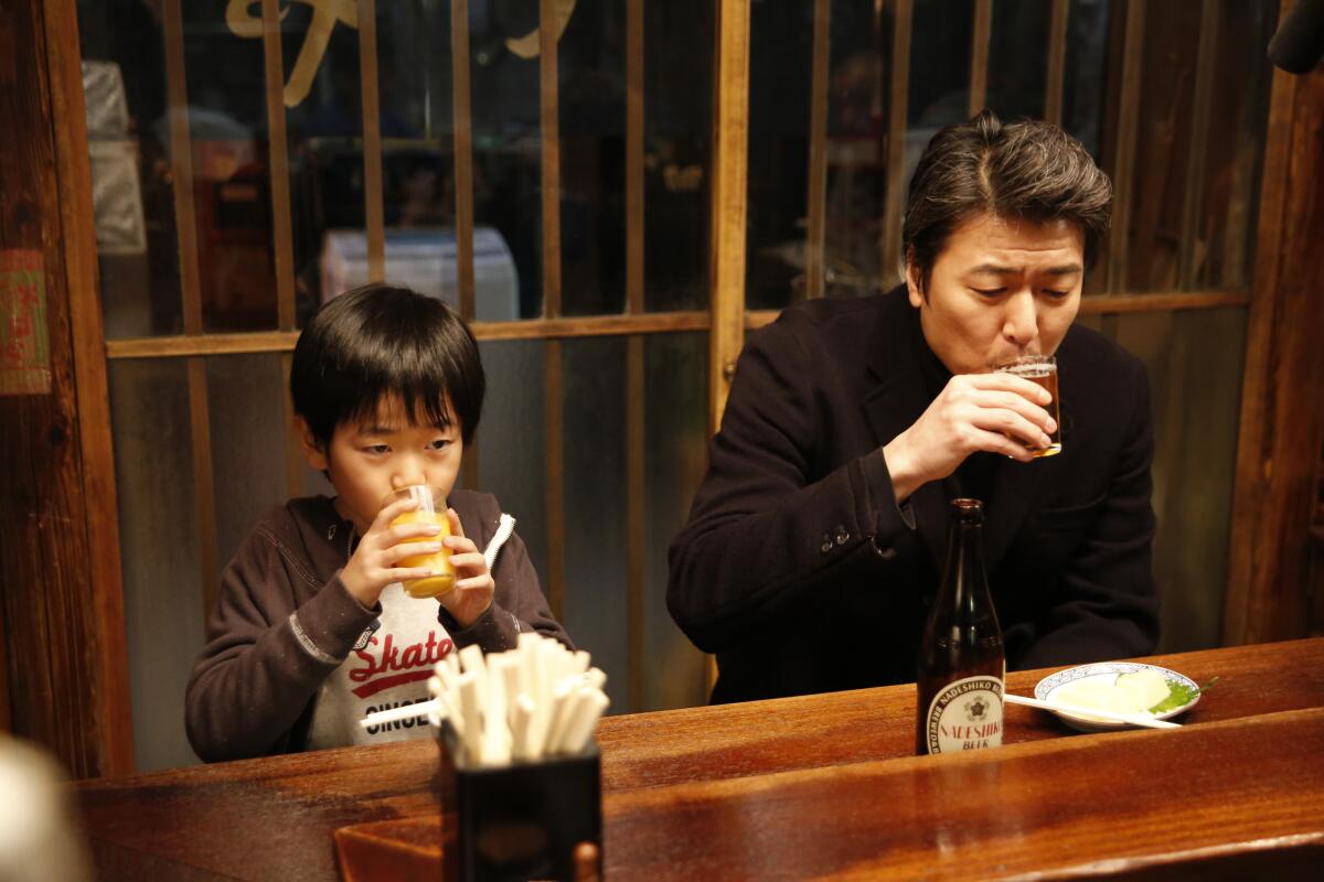 A man and his son both drinking from cups at a restaurant