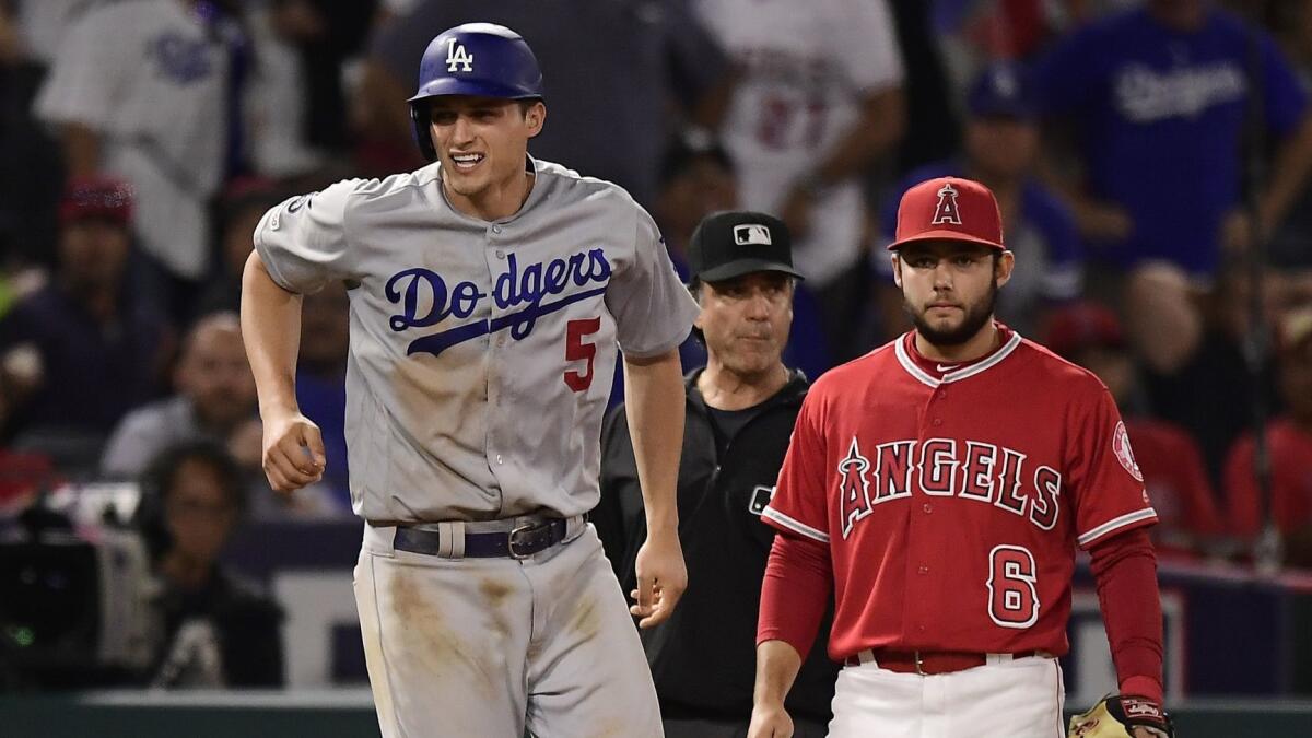 Dodgers' Corey Seager, left, winces after injuring himself while rounding third on a single by Alex Verdugo as Angels third baseman David Fletcher stands by during the ninth inning on Tuesday.