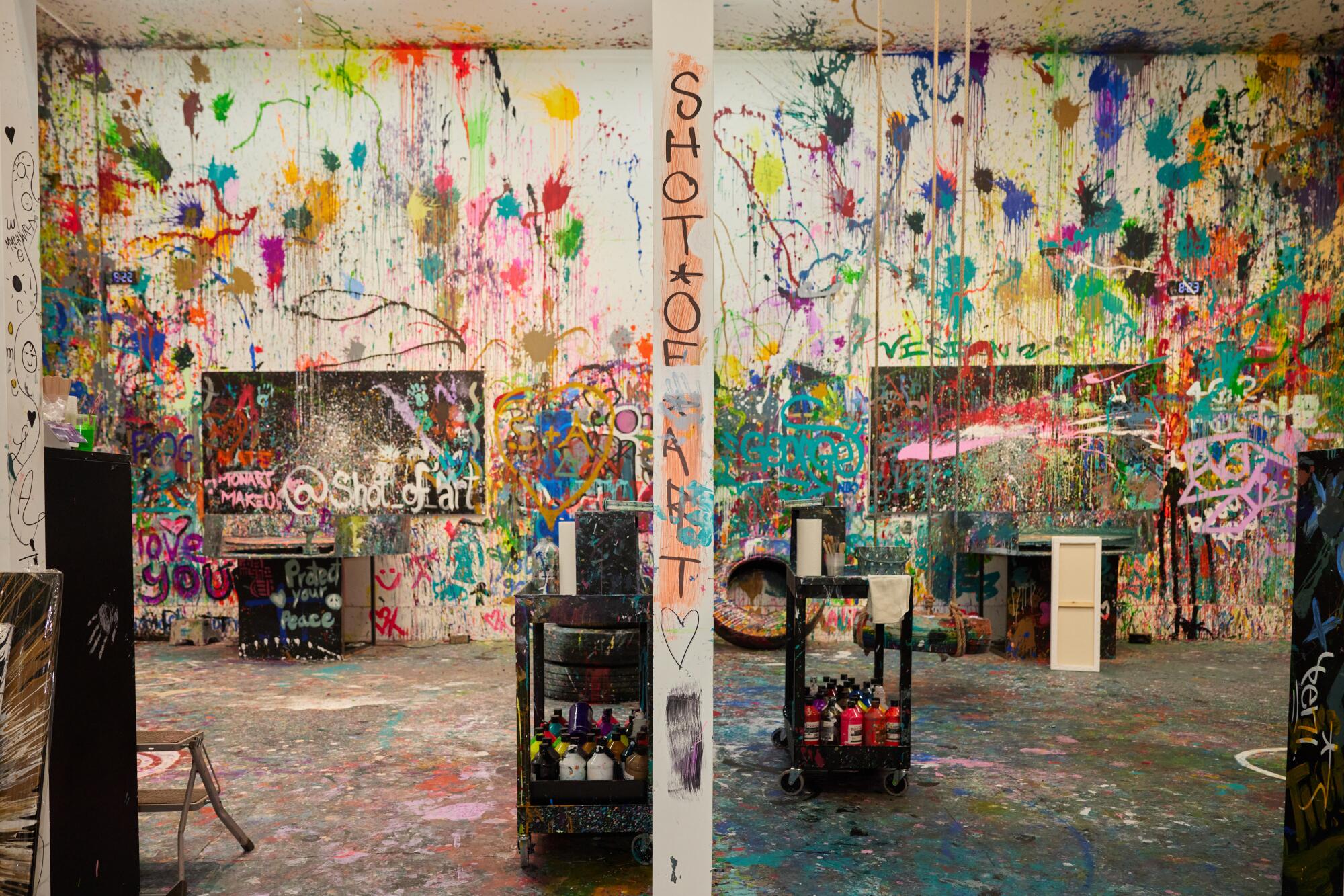 White walls are covered in splatters of multicolor paint.