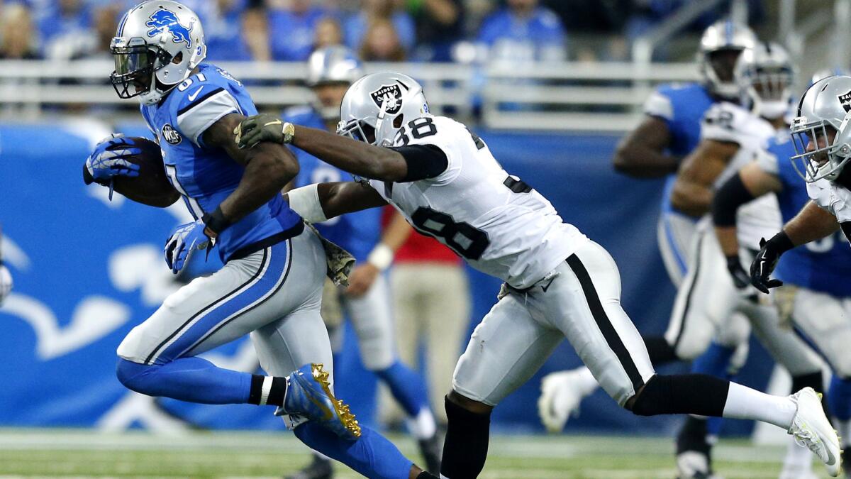 Raiders safety T.J. Carrie tries to tackle Lions wide receiver Calvin Johnson after a reception in the first half Sunday.