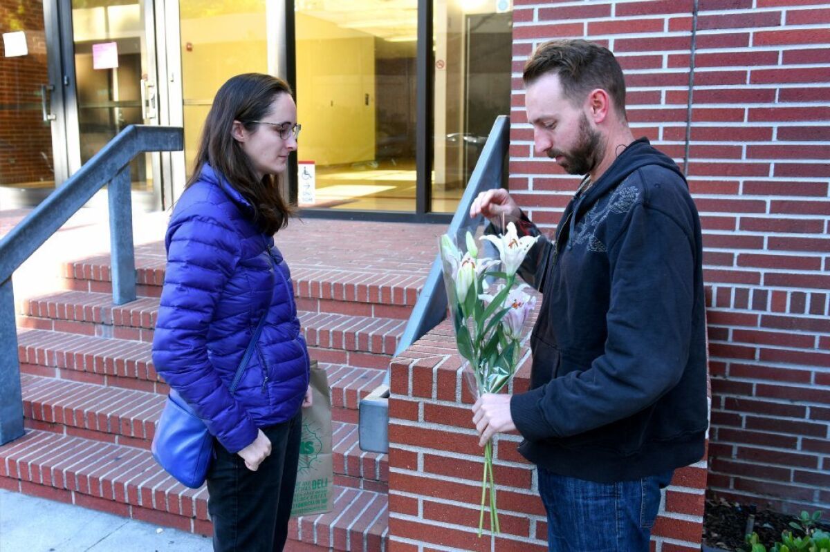 Dalton Combs, right, and Kate Swift-Spong bring flowers to the office of USC professor Bosco Tjan, who was stabbed to death Friday. A graduate student has been arrested in the slaying, according to the L.A. Police Department. Combs was Tjan's former student.
