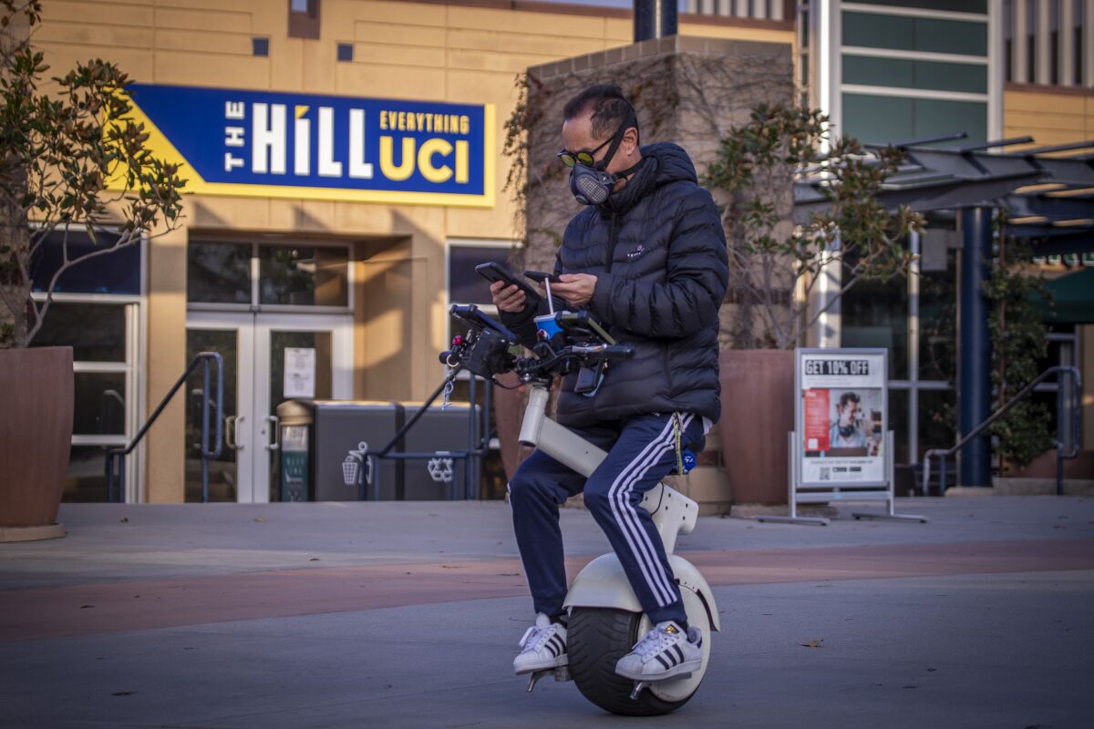 A person rides a one-wheeled scooter.