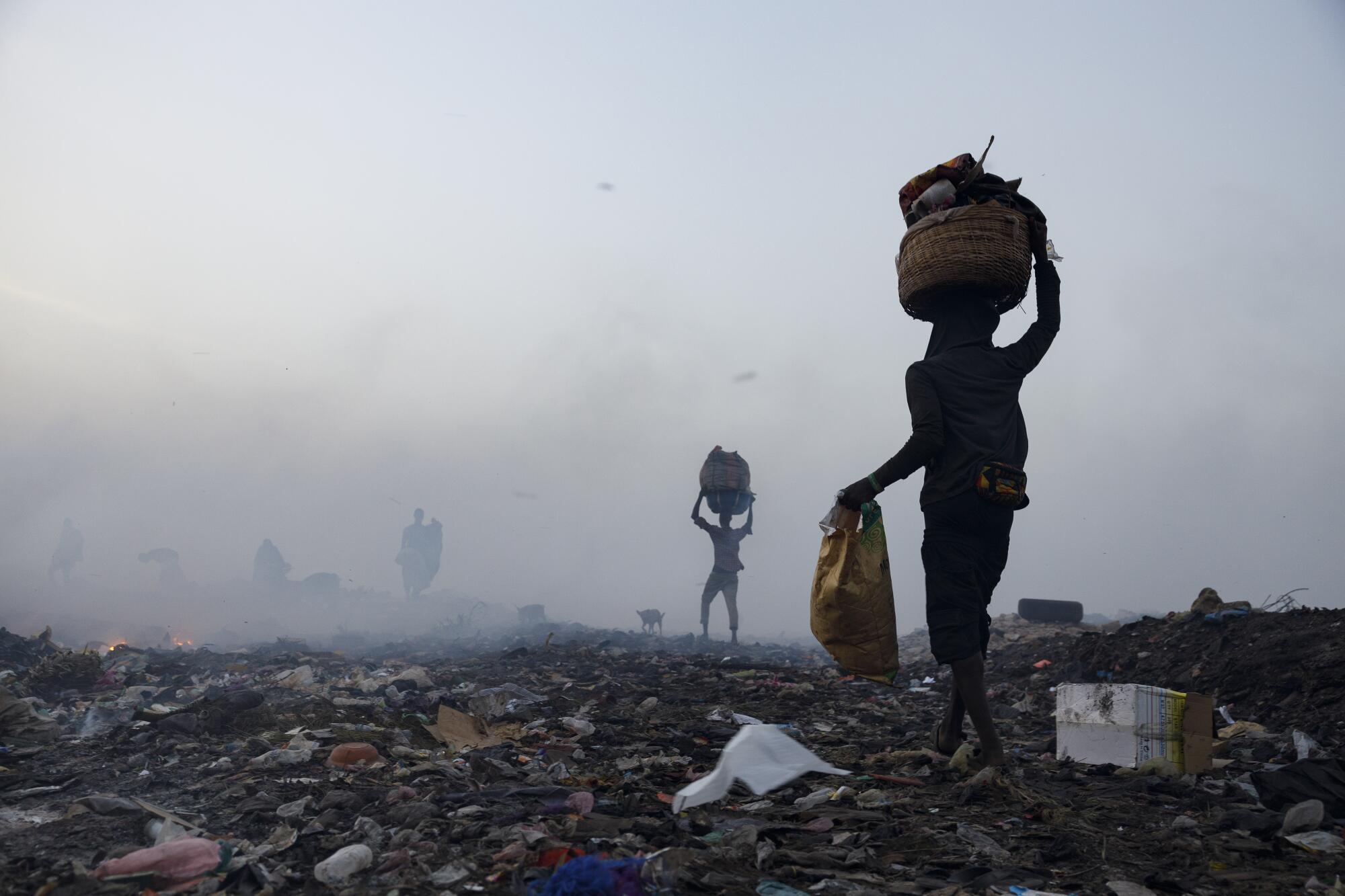 Young men with baskets on their head as smoke rises