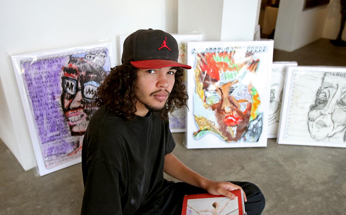 Julian St. John, an artist who has struggled with mental illness, sits among his most notable work that will be showcased at a one-night show at the Laguna Gallery of Contemporary Art.