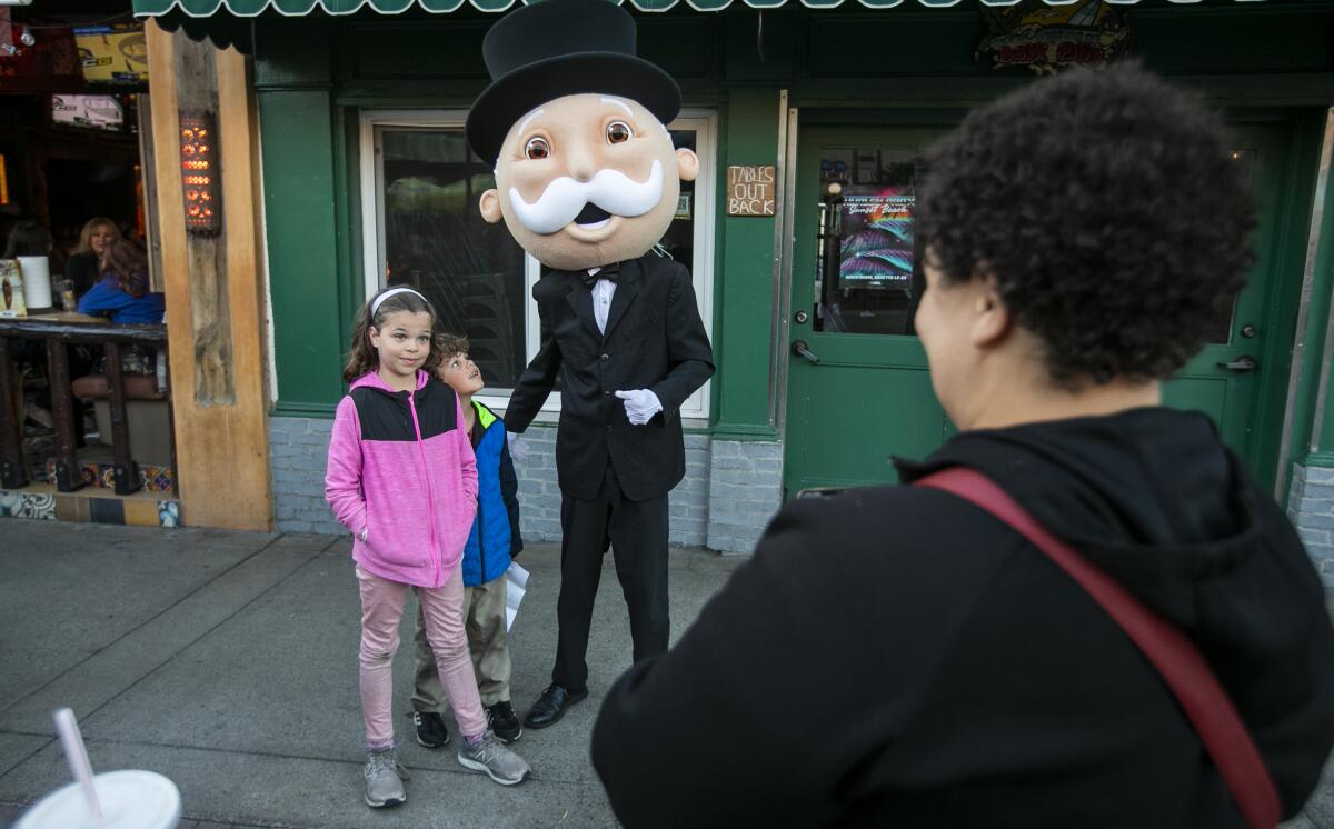 Emma Cooper and her brother Luke, take pictures with Mr. Monopoly on Tuesday in Huntington Beach,