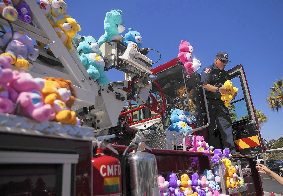 Costa Mesa Fire Department engineer Steve Savage holds one of approximately 200 Care Bears on a Costa Mesa fire truck on Friday.