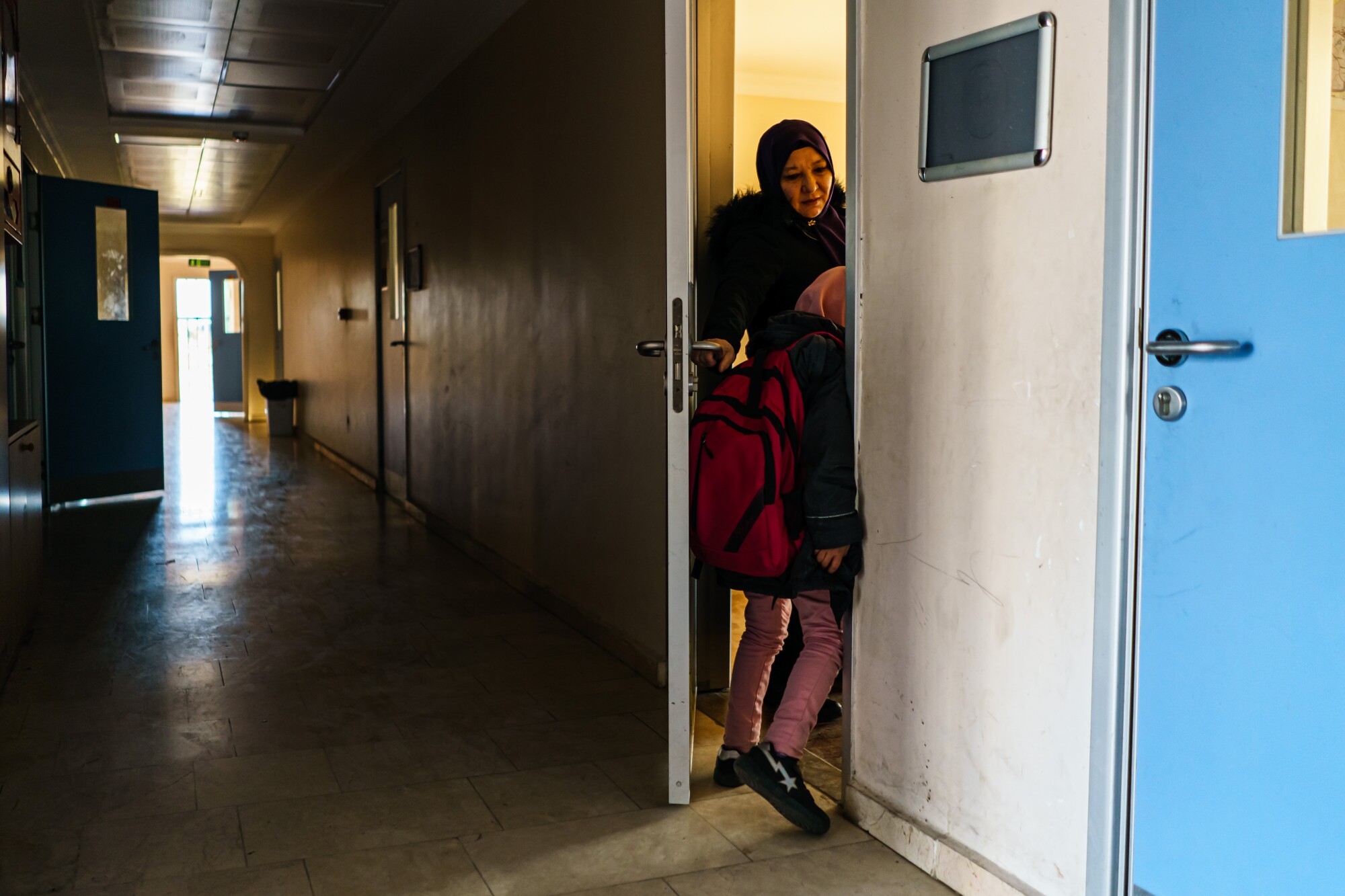 A child in a backpack slips through a school door.