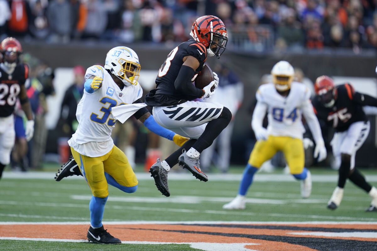 Cincinnati Bengals' Tyler Boyd (83) makes a catch against Los Angeles Chargers' Derwin James (33) during the second half of an NFL football game, Sunday, Dec. 5, 2021, in Cincinnati. (AP Photo/Michael Conroy)