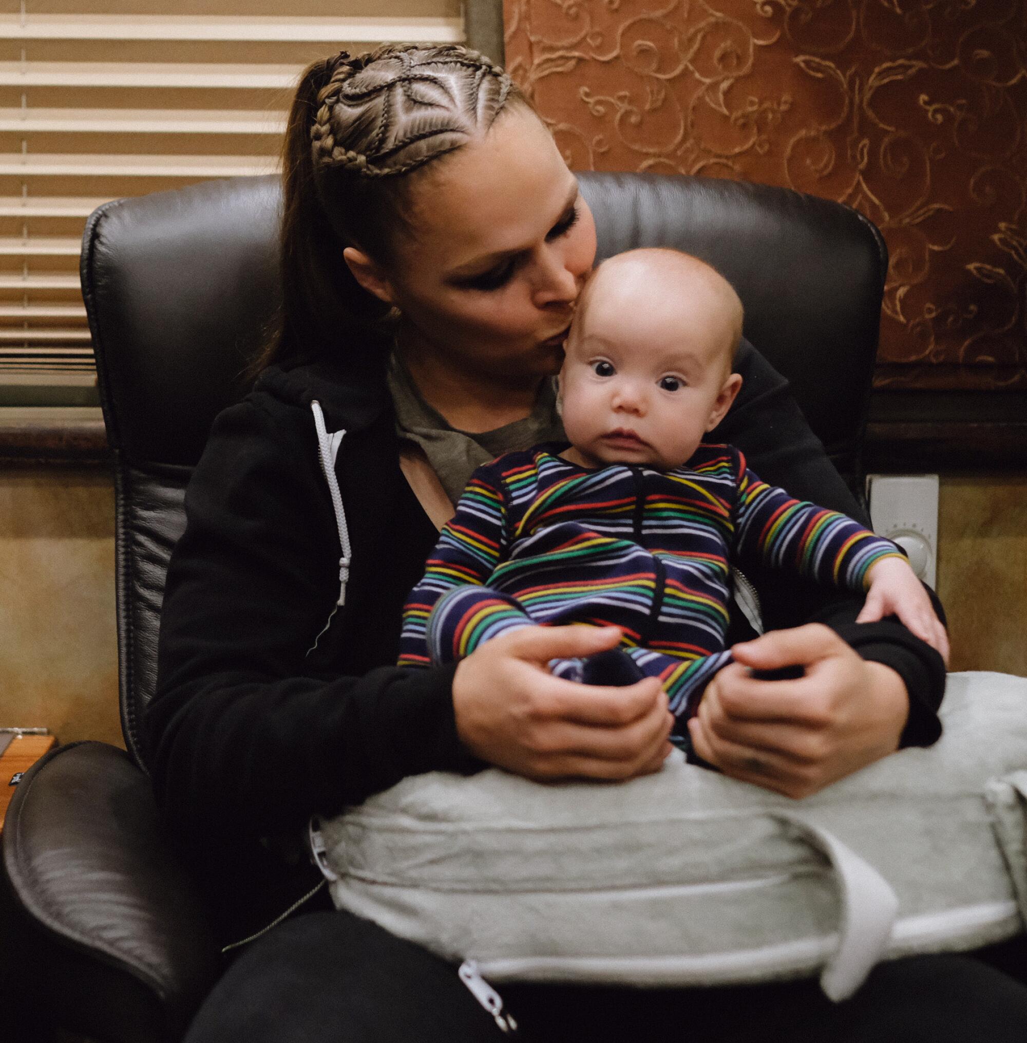 Ronda Rousey kisses the head of daughter La’akea Browne, who is sitting in her mother's lap.