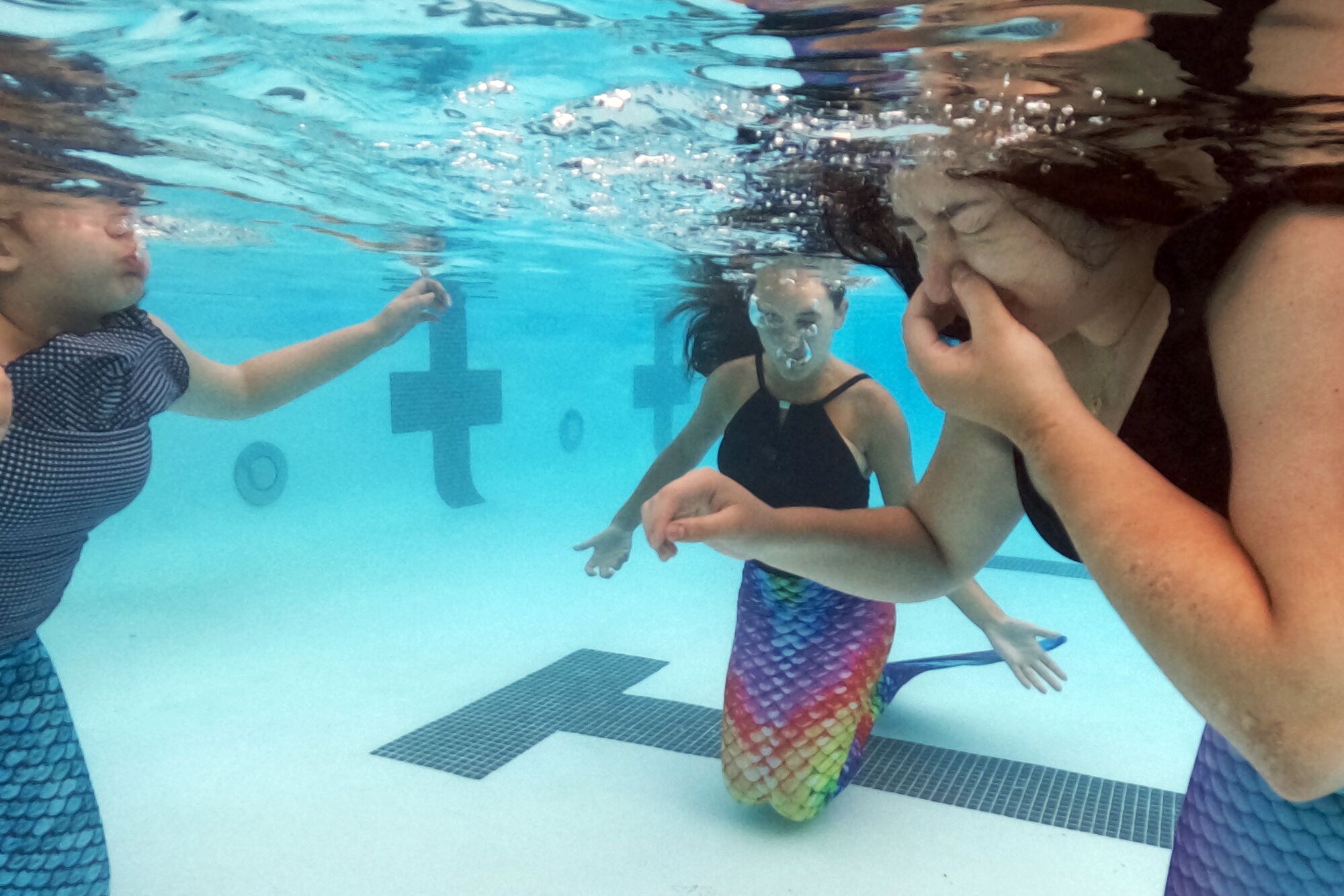 Hannah Jimenez, left, and Maria Espitia, right, take a mermaid lesson from instructor Emily Jordan.