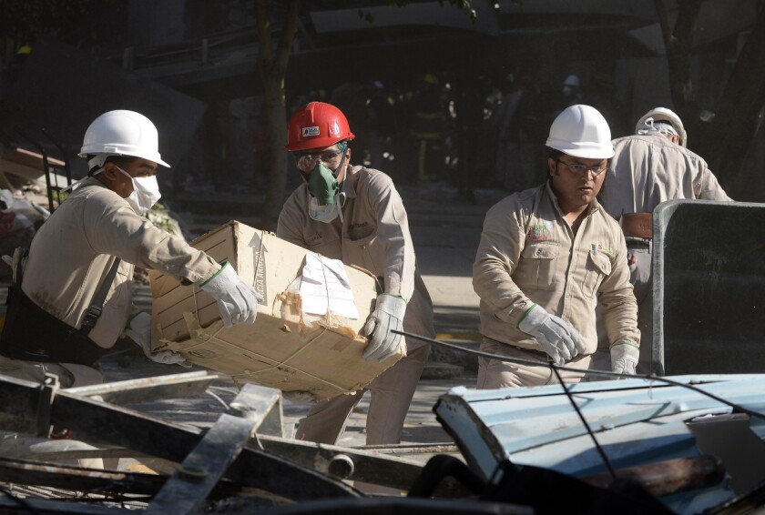 Pemex workers remove items from the headquarters of the state-owned Mexican oil company in Mexico City on Friday after an explosion the day before.