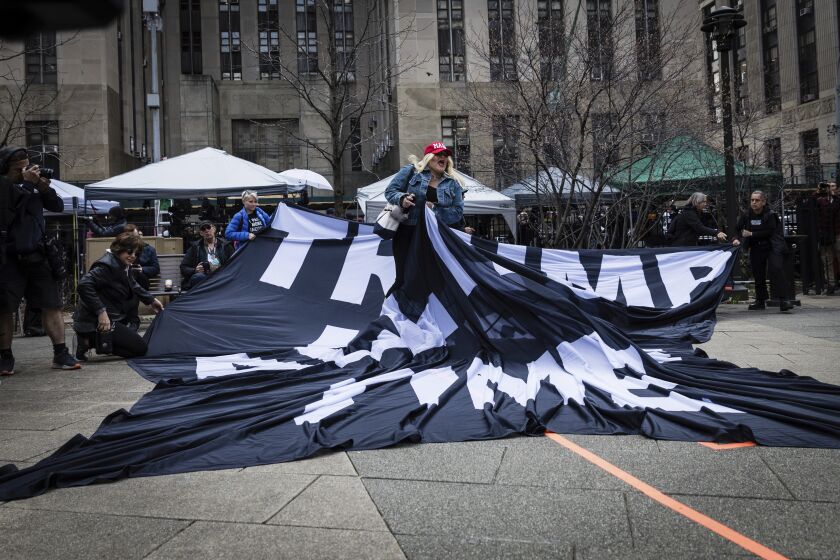 A supporter of former President Donald Trump pulls up an anti-Trump banner off the ground at the Collect Pond Park across the street from the Manhattan District Attorney's office in New York on Tuesday, April 4, 2023. Trump, who faces multiple election-related investigations, will surrender and be arraigned on criminal charges stemming from 2016 hush money payments. (AP Photo/Stefan Jeremiah)