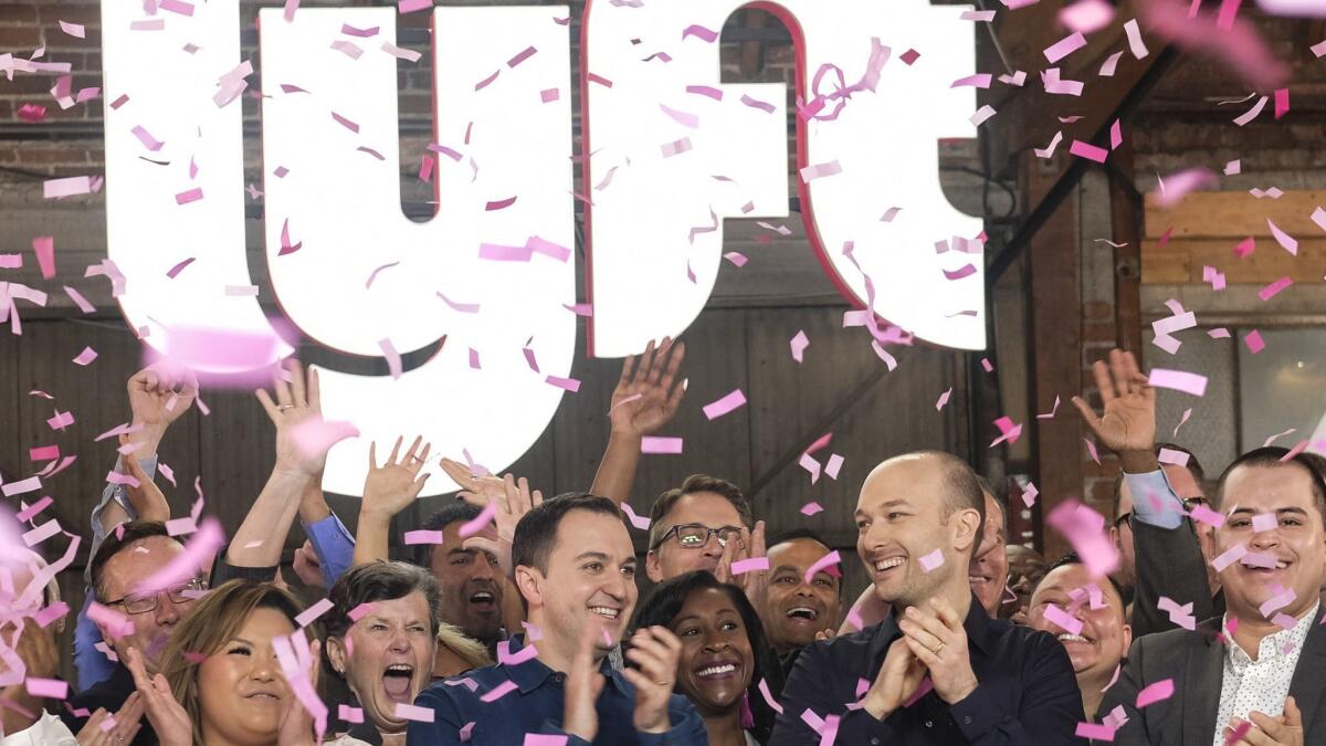 Lyft co-founders John Zimmer, left, and Logan Green cheer as they ring the Nasdaq opening bell celebrating the company's initial public offering on March 29 in Los Angeles.