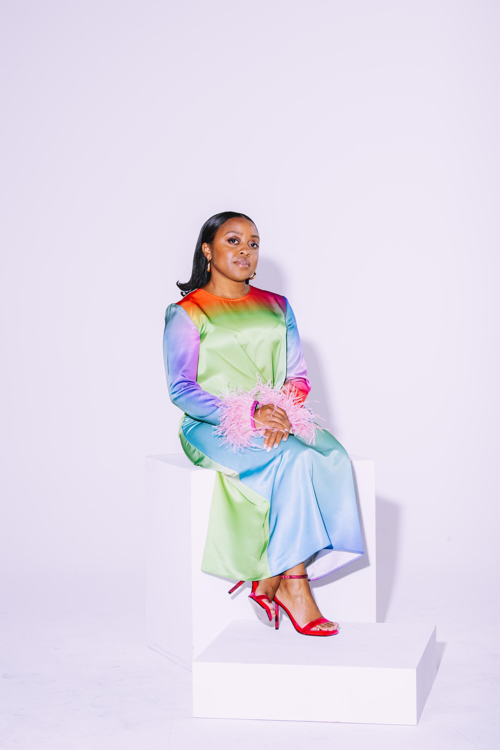 A woman in a colorful dress poses in a photo studio