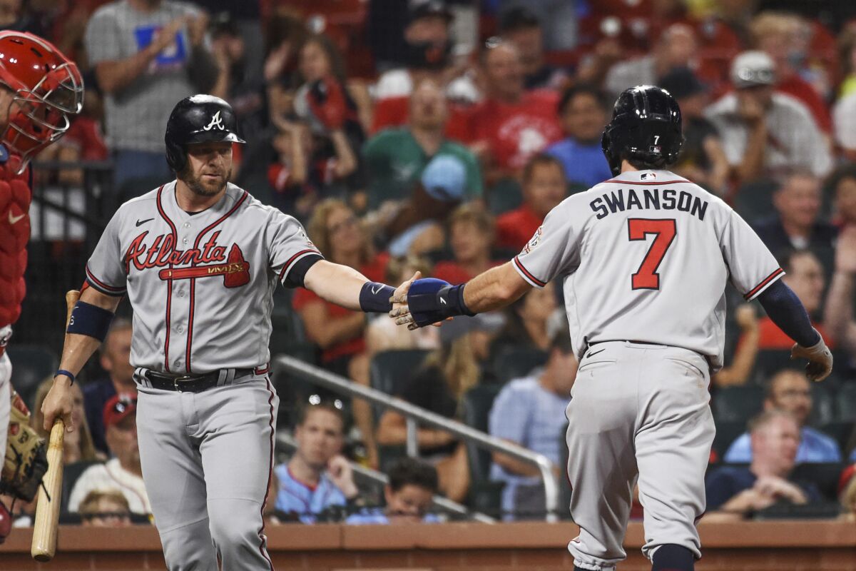 Atlanta Braves' Dansby Swanson, right, is congratulated by Stephen Vogt after scoring a run during the eighth inning of the team's baseball game against the St. Louis Cardinals on Thursday, Aug. 5, 2021, in St. Louis. (AP Photo/Joe Puetz)