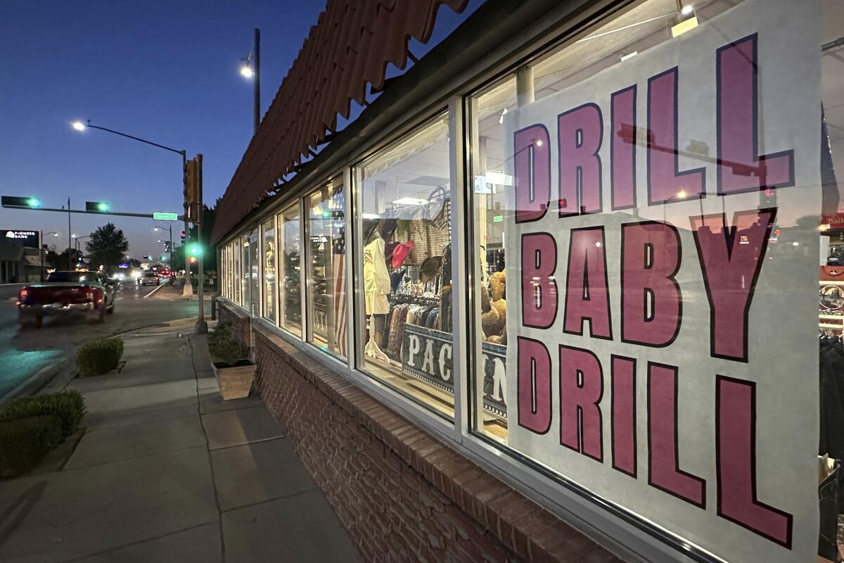 A sign in support of the oil and natural gas industry is displayed in a shop window