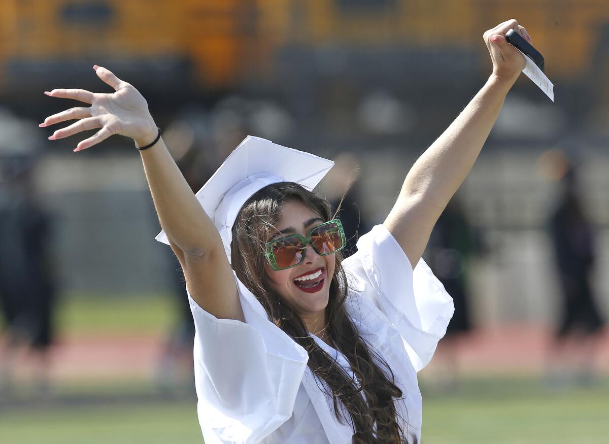 A happy graduate waves to family in the audience as she walks into the Huntington Beach High graduation ceremony on Tuesday.